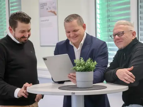Zwei Mitarbeiter der Firma Granzow, die sich amüsant am Drucker unterhalten.